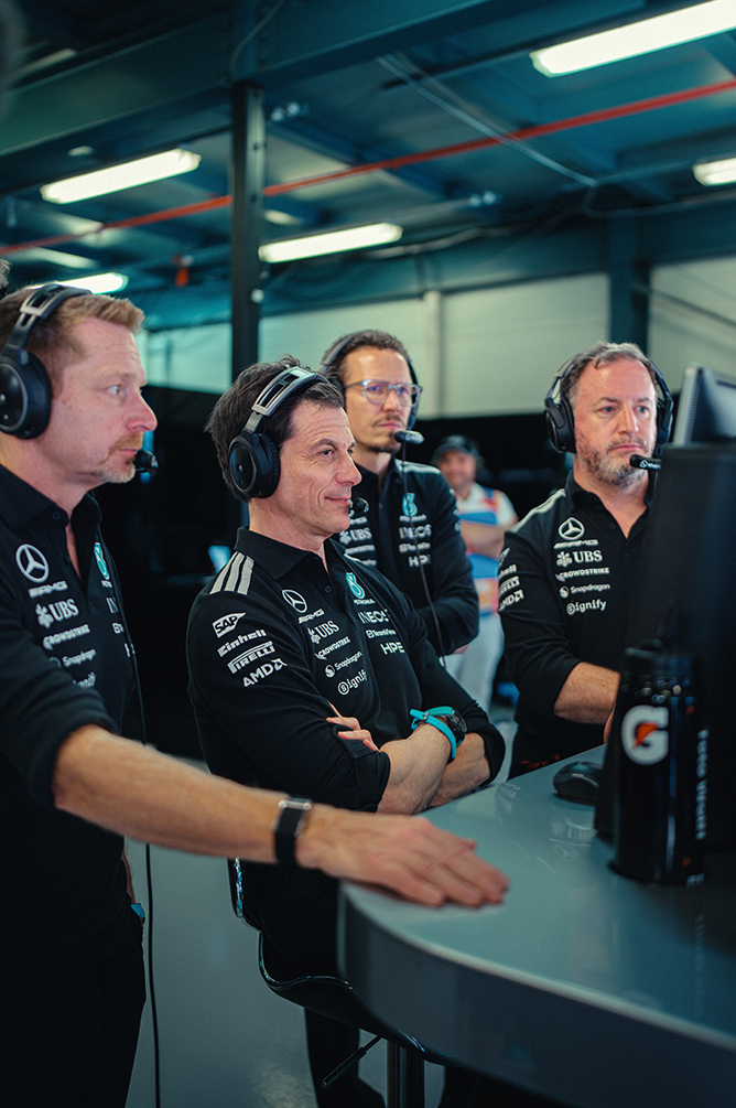 Formula 1 team members wearing headsets monitoring the race from the pit wall.